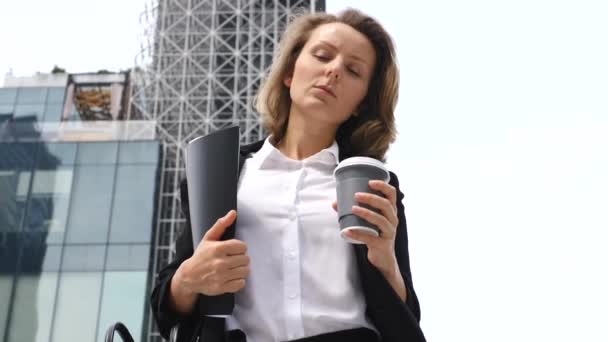Porträt einer seriösen Geschäftsfrau, die mit Kaffee im Freien spaziert - Filmmaterial, Video