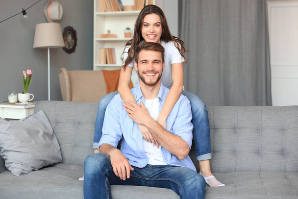 Beautiful woman with boyfriend spending quality time together on sofa at home in the living room. - Photo, Image