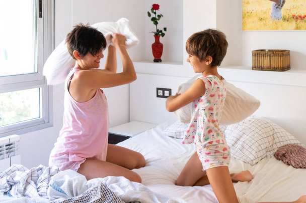 Matka i córka mający zabawny Pillow walka na łóżko. - Zdjęcie, obraz
