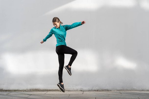 Nuori aikuinen urheilullinen nainen hyppää seinää vasten ulkona
 - Valokuva, kuva