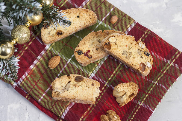 Biscotti tradizionali italiani o biscotti cantuccini con nocciole, mandorle, noci su un tovagliolo rosso-verde vicino all'albero di Natale. Natale e Capodanno cottura
. - Foto, immagini