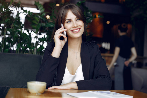 Businesswoman sitting at the table in a cafe and working - Foto, Bild