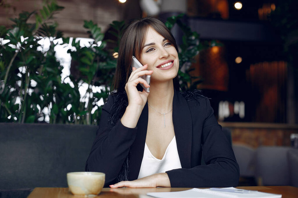 Businesswoman sitting at the table in a cafe and working - Foto, afbeelding