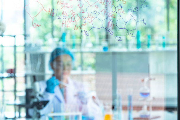 Blur científica mujer asiática, investigador, técnico, o estudiante llevó a cabo la investigación química y sentarse después de tablero de vidrio en el laboratorio
 - Foto, Imagen