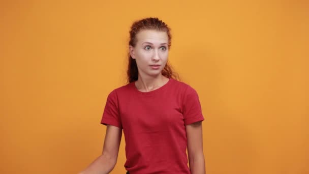 Młoda kobieta w czerwonej koszuli celująca w siebie, pytająca o wyraz twarzy - Materiał filmowy, wideo
