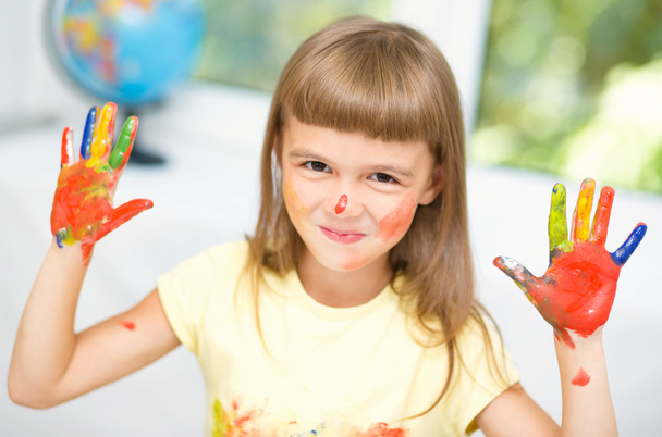 Portrait of a cute girl playing with paints - 写真・画像