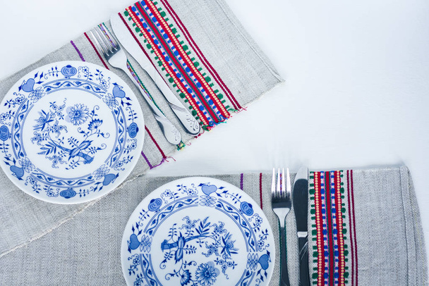 Table setting for dinner: white and blue plates, a fork, a knife - Φωτογραφία, εικόνα