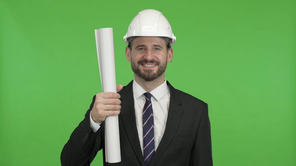 Веселый инженер показывает строительный план против Chroma Key
 - Фото, изображение