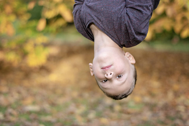 Portrait image du garçon d'âge préscolaire suspendu à l'envers en plein air
 - Photo, image