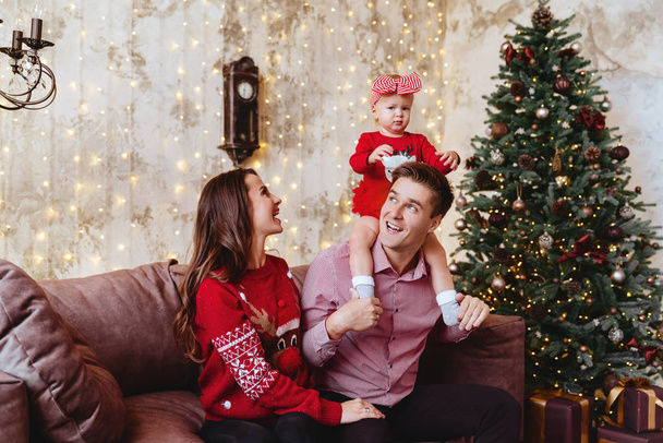 Jonge moeder, vader en haar dochtertje bij een kerstboom - Foto, afbeelding