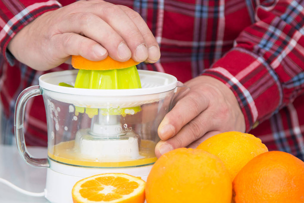 man making orange juice with juicer - Zdjęcie, obraz