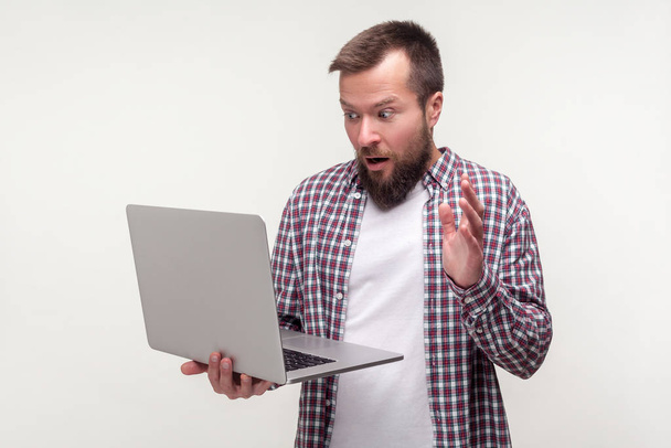 Портрет недовольного бородатого человека снимает руку с клавиатуры ноутбука
 - Фото, изображение