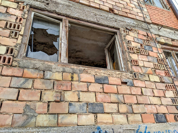 Stary zrujnowany dom z rozbitymi szybami i rozbitymi cegłami opuszczony na przedmieściach rozpadający się jako pusty dom i włamywacze. - Zdjęcie, obraz