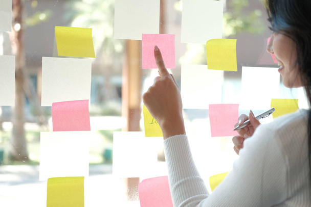 επιχειρηματίας γυναίκα που σκέφτεται σχεδιασμό με αυτοκόλλητες σημειώσεις για gla - Φωτογραφία, εικόνα