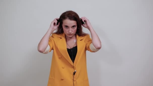 Caucasian young woman pulls on head headphones, looking sad - Imágenes, Vídeo