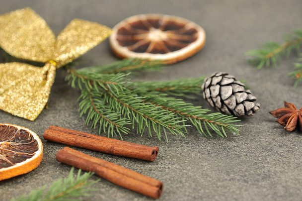 Christmas composition: Almonds, anise, pine cone, spruce branch, orange, cinnamon sticks on a dark background. Close-up. - Φωτογραφία, εικόνα