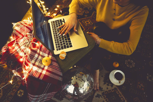Beautiful young woman shopping online on laptop in cozy Christma - Foto, afbeelding