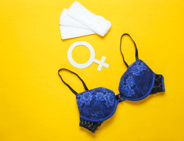 Días críticos para las mujeres, menstruación. Concepto minimalista de higiene femenina. Hermoso sujetador sexy, forros panty, símbolo de género en amarillo - Foto, imagen
