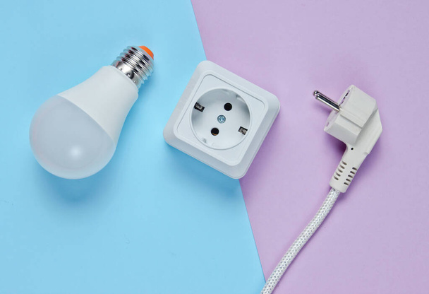 White plastic power socket, power plug, LED light bulb on pastel background. Top view - Fotó, kép