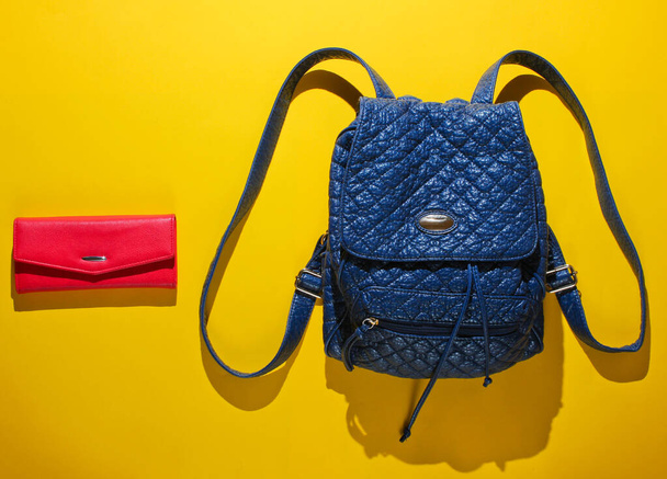 Leather backpack with straps and red purse on yellow background. Top view, minimalism fashion - Photo, Image