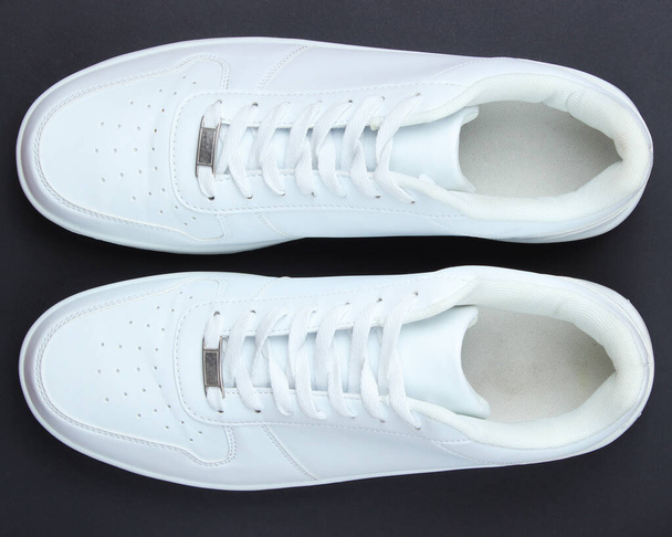 Fashionable white sneakers on a black background. Top view - Photo, Image