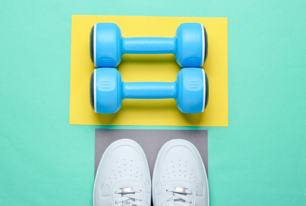White sneakers, plastic dumbbells on colored background. Sport concept. Top view - Foto, Imagen