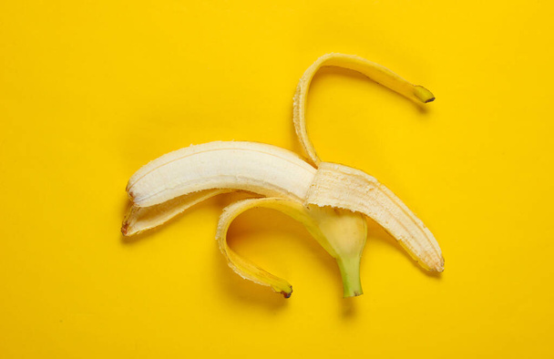 Minimalism fruit concept. Opened ripe banana on a yellow background. Top view - Photo, Image