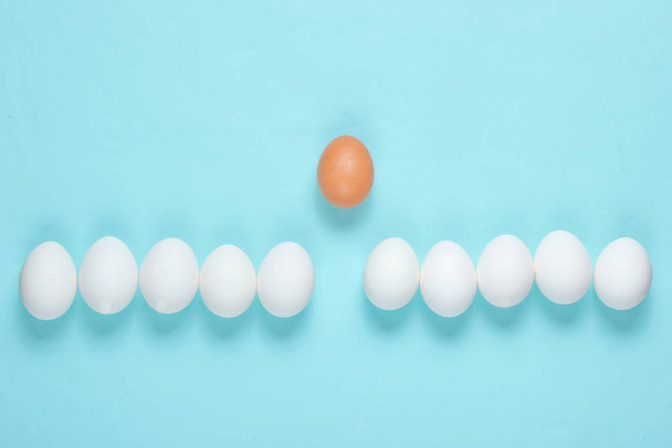Mobbing-Konzept mit Eiern auf blauem Hintergrund. Draufsicht, Minimalismus - Foto, Bild