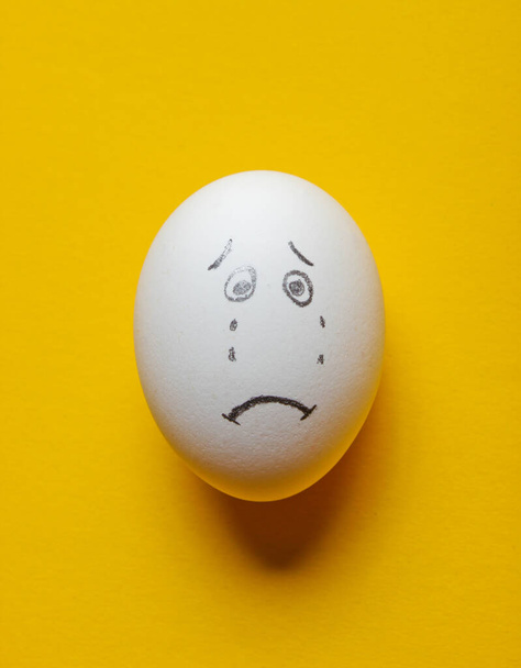Trauriges Gesicht Eier auf gelbem Hintergrund. Ansicht von oben - Foto, Bild