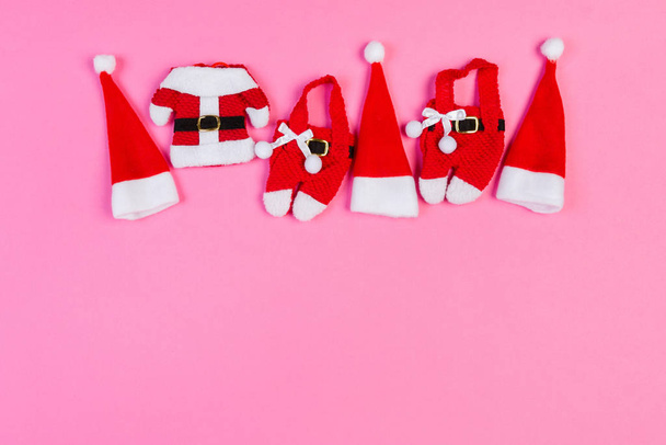 Draufsicht auf bunten Urlaubshintergrund aus Nikolausmützen und -kleidung. Frohe Weihnachten mit Kopierraum - Foto, Bild