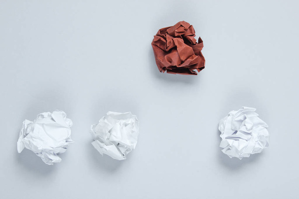 The concept of uniqueness, racial discrimination. White and brown crumpled paper balls on gray background. Top view, minimalism business - Photo, image