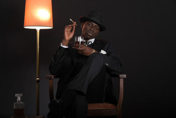 ρετρό αφρικανικός Αμερικανός γκάνγκστερ άνδρας ο οποίος φορούσε ριγέ κοστούμι και γραβάτα - Φωτογραφία, εικόνα