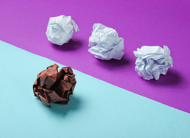 The concept of uniqueness, racial discrimination. White and brown crumpled paper balls on purple blue background. Minimalism business - Foto, Imagem