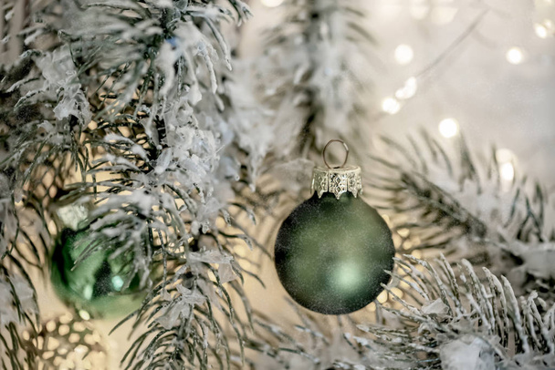 Χριστούγεννα και Πρωτοχρονιά ευχετήρια κάρτα. Όμορφες πράσινες μπάλες, κλαδιά πεύκου και μια γιρλάντα στο χιόνι. - Φωτογραφία, εικόνα