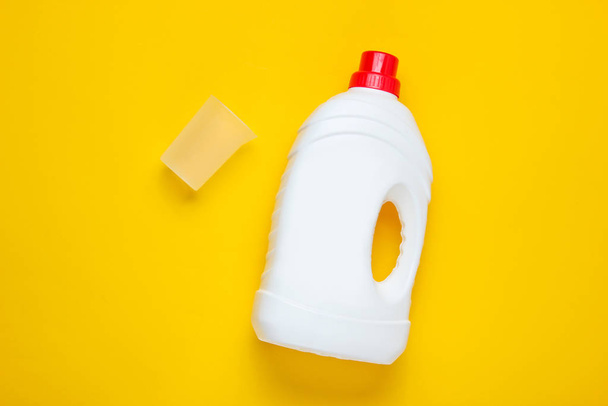 Бутылка геля для мытья, пустой мерный контейнер на желтом фоне. Вид сверху
 - Фото, изображение