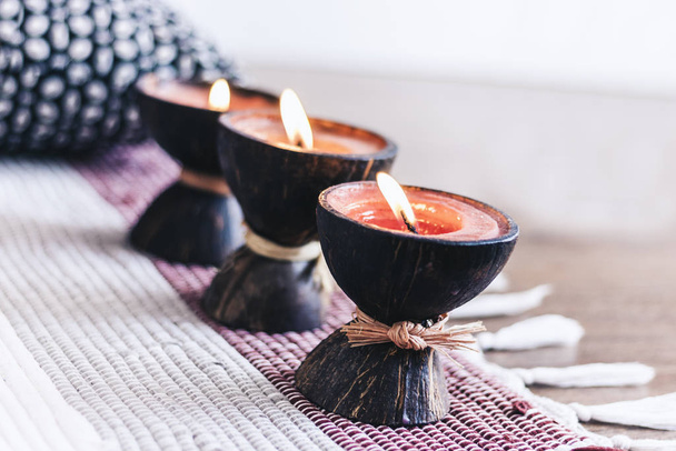 Burning spa aroma candle in coconut shell on multi-colored rug b - 写真・画像