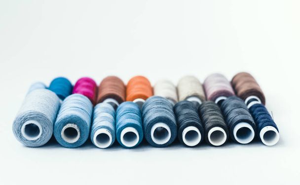 Colored sewing thread coils on white background with copy space  - Foto, Bild