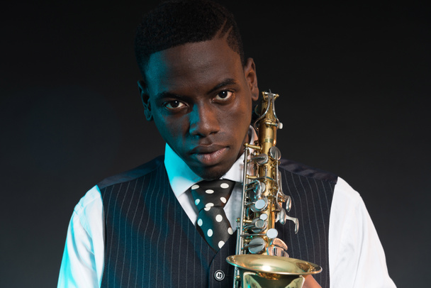 Retro Afro-Amerikaanse jazzmuzikant houden zijn saxofoon. slijtage - Foto, afbeelding