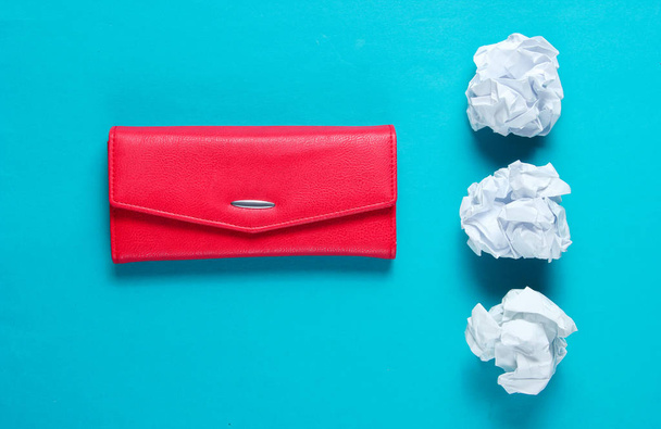 Minimal concept. Crumpled paper balls, red leather wallet on blue background - 写真・画像