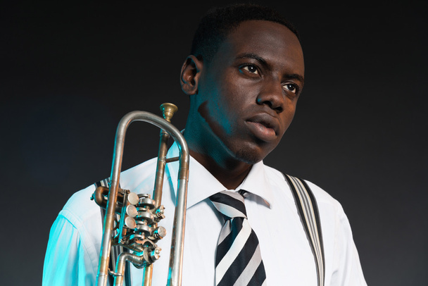 Retro-afrikkalainen jazzmuusikko pitelee trumpettiaan. Kuluminen
 - Valokuva, kuva
