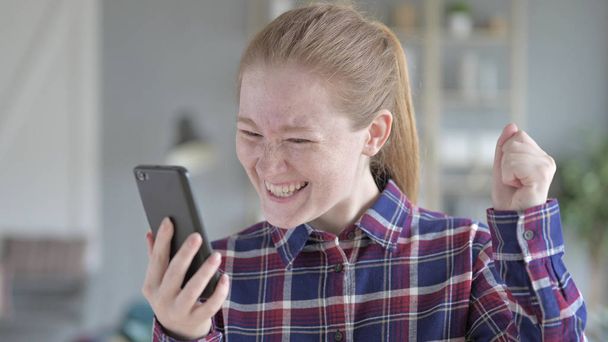 Η νεαρή γυναίκα χρησιμοποιώντας το τηλέφωνο και αίσθημα ενθουσιασμένος - Φωτογραφία, εικόνα