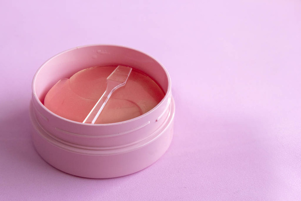 Kan hydrogel cosmetische ooglapje voor huidverzorging op roze achtergrond. Product voor face lifting, anti-aging rimpels, kopieerruimte - Foto, afbeelding