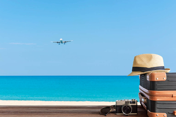 Літні подорожі та план з старовинним багажем і старою камерою на піщаному пляжі. Подорожі у відпустку, літак і блакитне небо фону. Концепція літа та подорожей
 - Фото, зображення