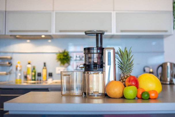 Κάνοντας χυμό φρούτων με αποχυμωτή μηχάνημα στην κουζίνα του σπιτιού, υγιεινή διατροφή έννοια του τρόπου ζωής - Φωτογραφία, εικόνα