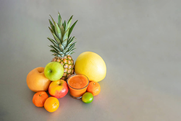 Verschillende tropische vruchten en oranje smoothie op grijze achtergrond, gezond eten lifestyle concept - Foto, afbeelding