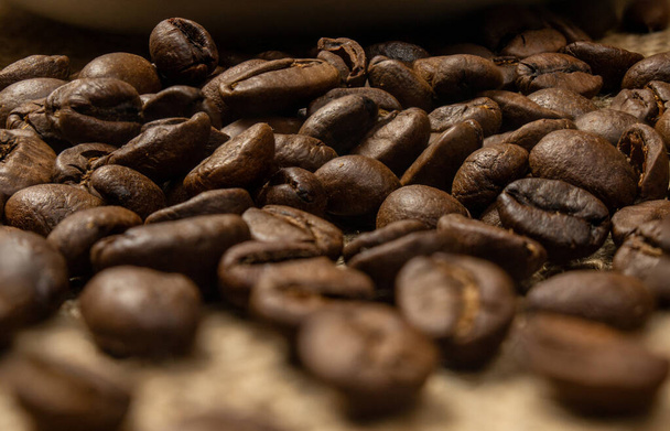 Roasted coffee beans. Coffee beans scattered on the table. - Photo, Image
