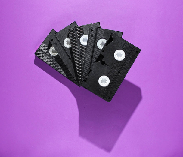 Stack of retro video cassettes on purple background. Top view - Photo, Image
