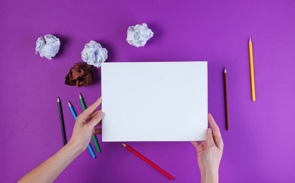 Žena bude kreslit barevnými tužkami na fialovém pozadí se zmačkanými papírovými kuličkami. Horní pohled - Fotografie, Obrázek