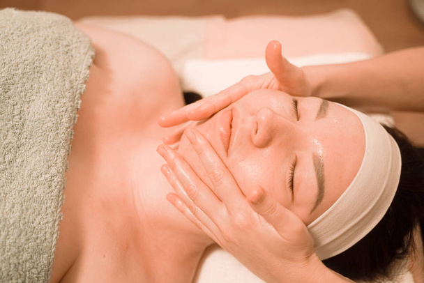 Beautiful young woman getting a face massage treatment at beauty salon - Фото, зображення