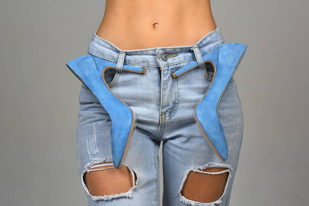 Sexy girl with a naked stomach in jeans and blue high-heeled shoes. Fashionable clothes and shoes. Style and fashion. Denim background. Modern woman, style icon. Blue concept. Designer of clothes. - Foto, immagini